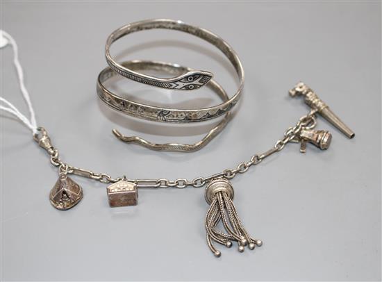 A modern silver and niello serpent bangle and a white metal tassle bracelet hung with four assorted charms, gross weight 65 grams.